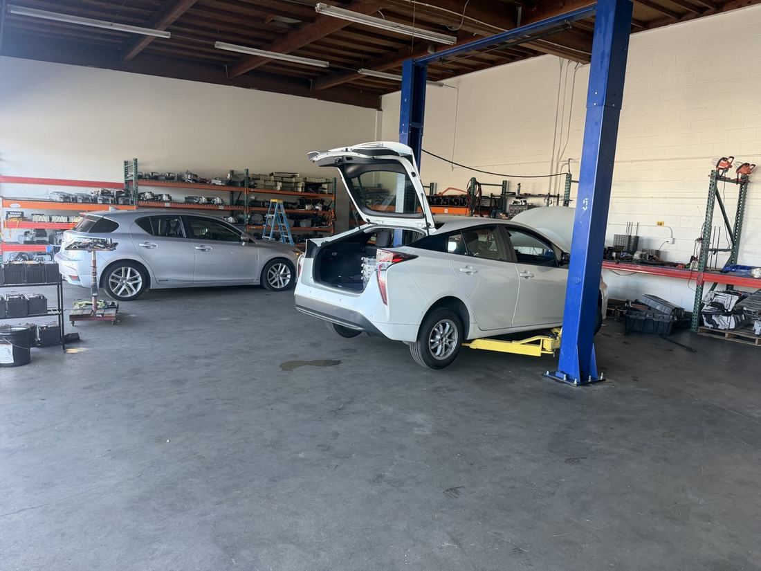 White Prius on the lift inside the shop